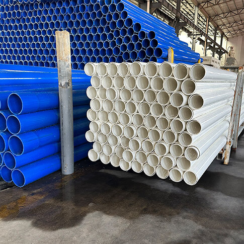 Blue and white rigid PVC pipes stacked inside the Puhui factory