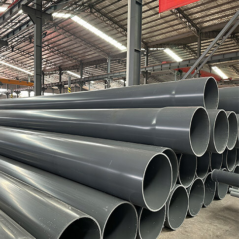 Large-diameter grey rigid PVC pipes stacked inside the Puhui factory
